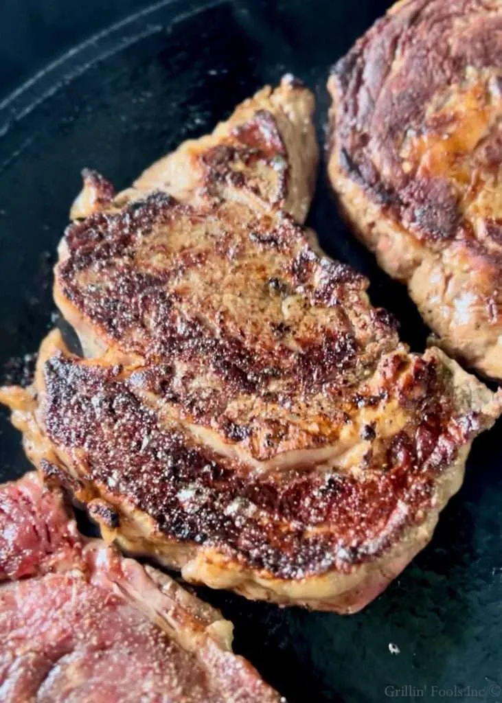 A ribeye steak with an amazing flavor crust on a cast iron griddle