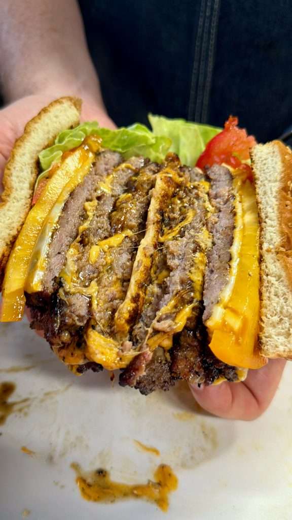 A cross section of a triple decker ground pork smash burger sliced in half