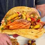 A grilled salmon taco with a fresh salsa all in a toasted corn torilla